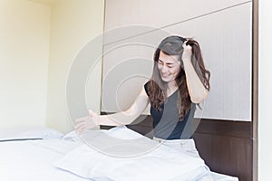 depress woman sitting on bed in room hitting a pillow