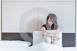 depress woman sitting on bed in room with lower head