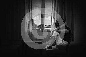 depress woman sitting on chair in room near window in white tone