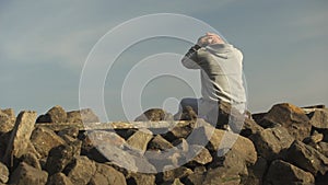 Depressed addicted regretting bad behavior, surrounded with stones near lake