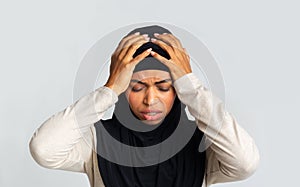Depressed afro muslim woman holding head in hands, regret about something