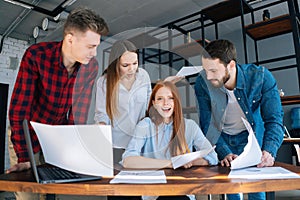 Depressed angry young business woman under stress throwing documents at desk looking at camera, multi-ethnic colleagues