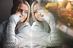Depressed/anxious young woman sitting by a large window