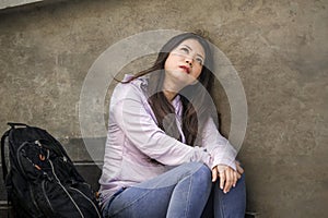 Depressed Asian American student woman or bullied teenager sitting outdoors on street staircase overwhelmed and anxious feeling