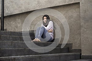 Depressed Asian American student woman or bullied teenager sitting outdoors on street staircase overwhelmed and anxious feeling