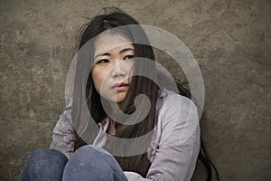 Depressed Asian American student woman or bullied teenager sitting outdoors on street staircase overwhelmed and anxious feeling