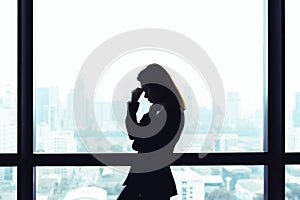 Depressed asian business woman standing at windows with city view background