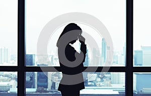 Depressed asian business woman standing at windows with city view background