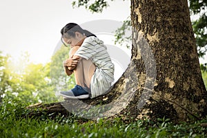 Depressed asian child girl was sitting alone crying and thinking about problems  at park,sad female teenage having psychological