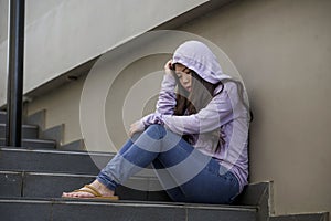 Depressed Asian Chinese student woman or bullied teenager girl sitting outdoors on street staircase victim of bullying feeling
