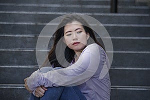 Depressed Asian Japanese student woman or bullied teenager sitting outdoors on street staircase overwhelmed and anxious feeling