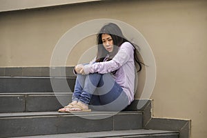 Depressed Asian Japanese student woman or bullied teenager sitting outdoors on street staircase overwhelmed and anxious feeling
