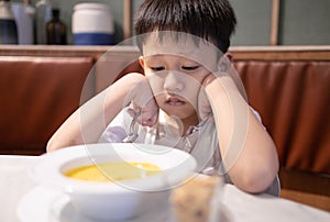 Depressed asian kid boy with anorexia,don`t have appetite,child kindergarten bored with food or boredom,refusing to eat vegetable