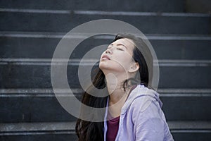 Depressed Asian Korean student woman or bullied teenager sitting outdoors on street staircase overwhelmed and anxious feeling