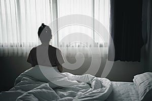 Depressed asian woman has sad and lonely feel sitting on the bed in the morning