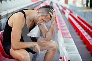 Depressed athlete man sitting head in hands on stadium seats photo
