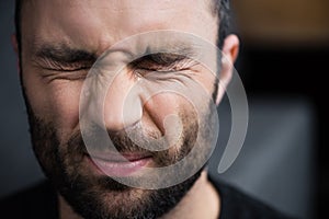 Depressed bearded man crying with closed eyes