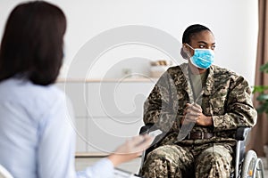 Depressed black military woman in wheelchair having therapy session with psychologist