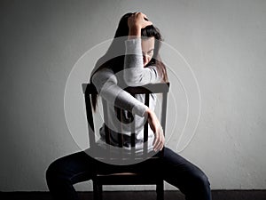 Depressed broken hearted woman sitting alone on a wooden chair