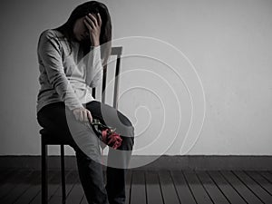 Depressed broken hearted woman sitting and crying with red rose photo