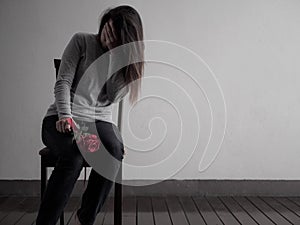 Depressed broken hearted woman sitting and crying with red rose photo