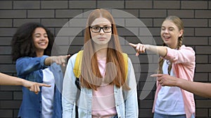 Depressed bullying victim eyeglasses looking camera, teenagers pointing fingers