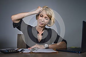 Depressed business woman working overwhelmed at office with laptop computer feeling exhausted suffering headache holding her head