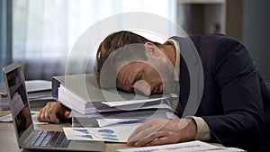 Depressed businessman lying on pile of folders, deadline pressure, exhaustion photo