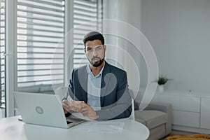 Depressed businessman man counting euro money working on computer at office desk and looking at camera, inflation