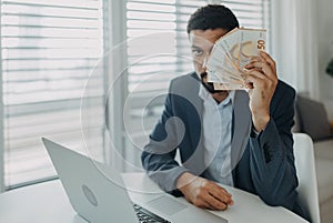 Depressed businessman man counting euro money working on computer at office desk and looking at camera, inflation