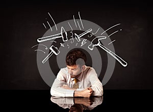 Depressed businessman sitting under hammer marks