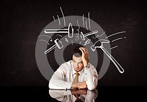 Depressed businessman sitting under hammer marks