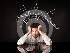 Depressed businessman sitting under hammer marks