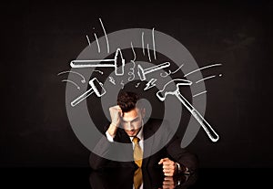 Depressed businessman sitting under hammer marks