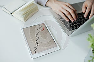 Depressed businessman typing laptop with bad stock market chart