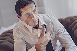 Depressed cheerless man holding his tie