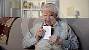 Depressed crying pensioner holding photo, old age loneliness, nostalgia sadness