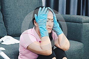 Depressed crying woman looks stressfully, keeps both hands on head, wears protective gloves, feels fatigue of busy day and