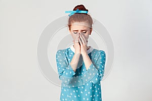 Depressed and crying young caucasian girl with ginger hair feeling ashamed or sick, covering face with both hands