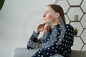 Depressed and dejected woman sitting on the sofa in the house