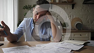 Depressed desperate man feeling worried about financial problem doing paperwork.