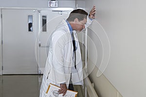 Depressed Doctor Leaning Against Wall photo