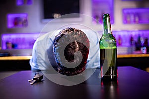 Depressed drunk man sleeping with his head on the table