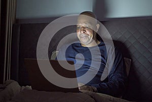 Depressed elderly black man. African American people using a notebook laptop computer on social media internet on bed in bedroom