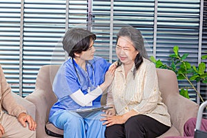 Depressed elderly female crying, young nurse consoling her at retirement home. Unhappy impaired man feeling lonely and sad