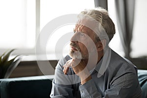 Depressed elderly man lost in thoughts mourning at home photo