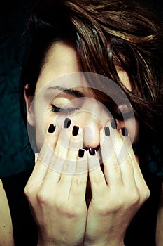 Depressed girl with closed eyes put her hands on her face vertical close up portrait.