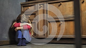 Depressed girl sitting on kitchen floor alone