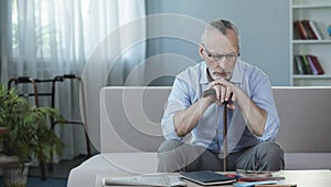 Depressed grandfather sitting on couch and thinking about future, nursing home