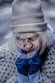 Depressed homeless woman trying to warm her hands